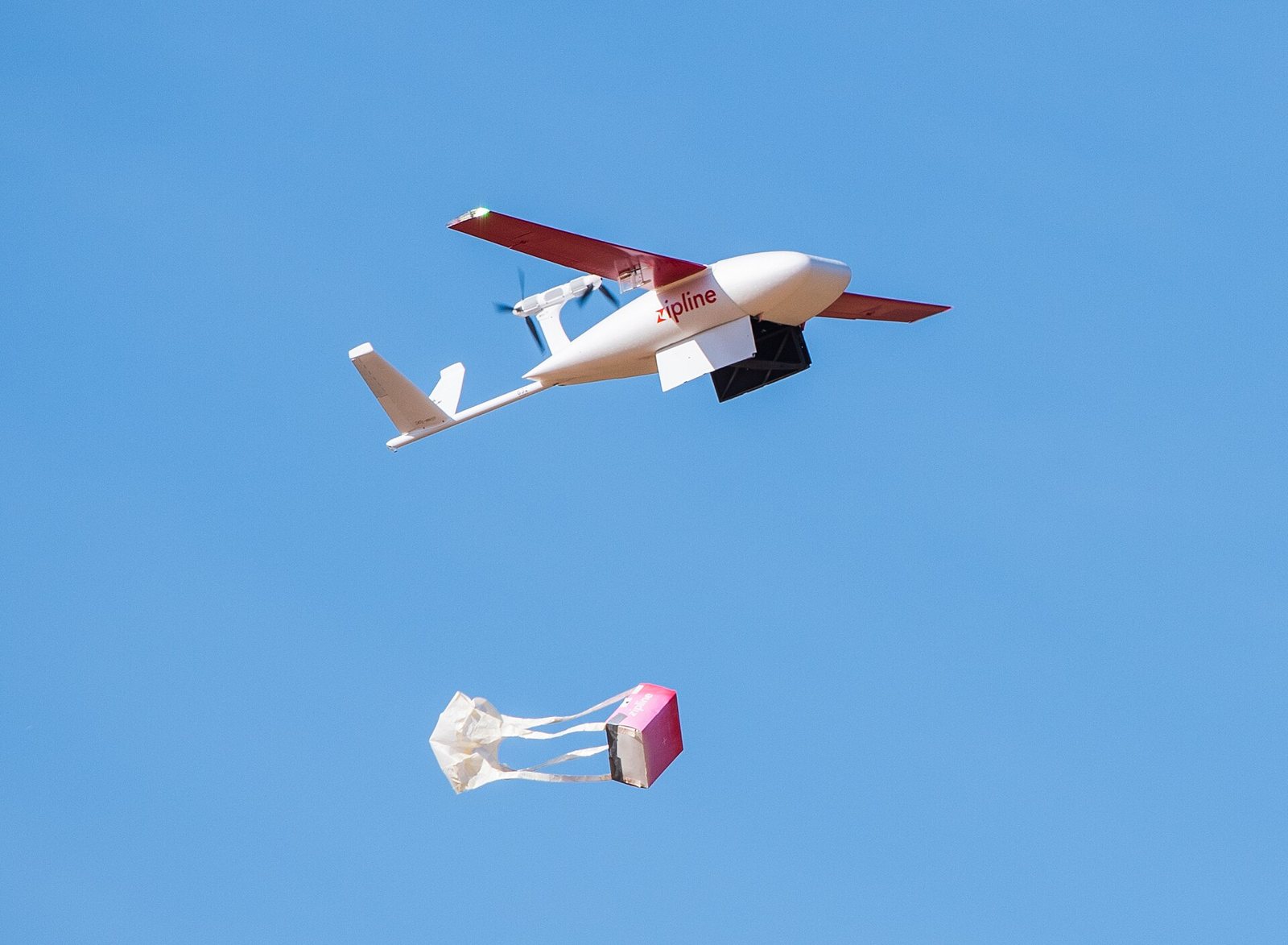 Zipline fixed-wing delivery drone releasing a parachute package